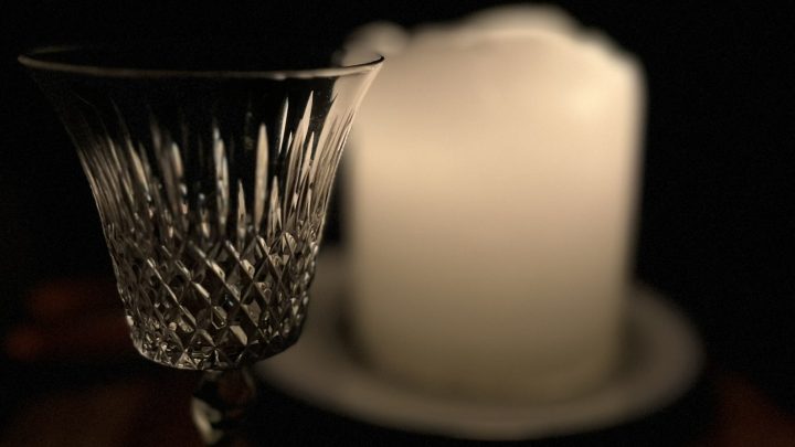 Single white candle burning beside a pretty glass